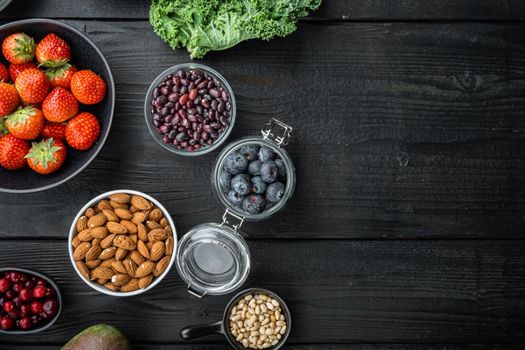 Healthy food and clean eating selection, top view with space for text, on black wooden background.