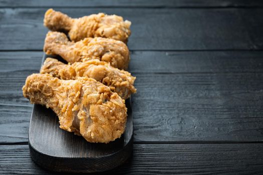 Crispy fried chicken drumstick on black wooden background, with space for text.
