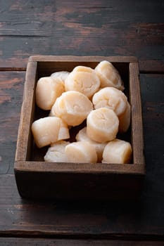 Fresh raw uncooked scallops, on dark wooden background