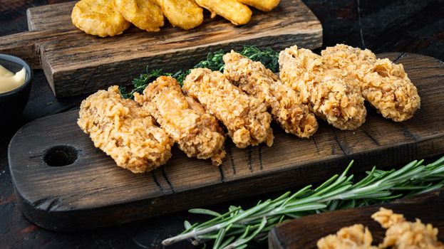 Breaded chicken wings cuts on old dark wooden table.