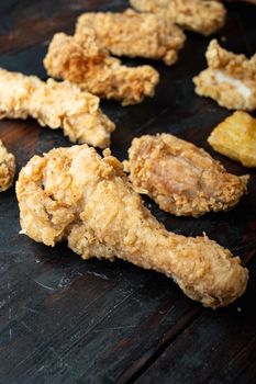 Crispy fried chicken parts on old dark wooden table.