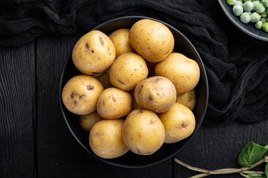 Pile of baby potatoe, top view, on black wooden background