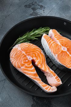 Slice of red fish trout on grill skillet, over grey background.