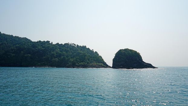 Travel by sea in Thailand by ship. View of the open ocean, green Islands and gray sky in smog. Green water with waves. Sailing between the Islands. Ship from different sides: stern, bow, rope, anchor.