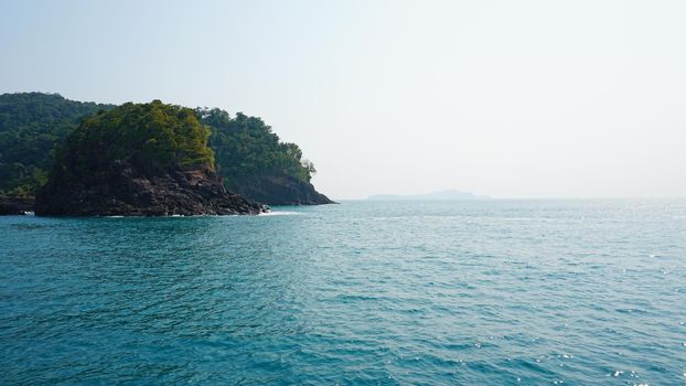 Travel by sea in Thailand by ship. View of the open ocean, green Islands and gray sky in smog. Green water with waves. Sailing between the Islands. Ship from different sides: stern, bow, rope, anchor.