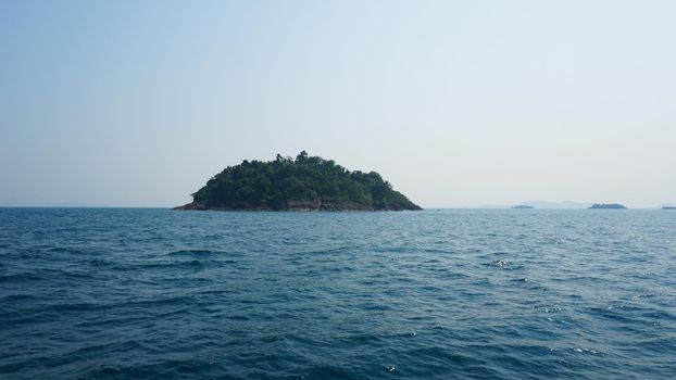 Travel by sea in Thailand by ship. View of the open ocean, green Islands and gray sky in smog. Green water with waves. Sailing between the Islands. Ship from different sides: stern, bow, rope, anchor.