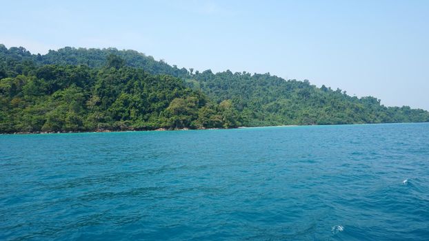 Travel by sea in Thailand by ship. View of the open ocean, green Islands and gray sky in smog. Green water with waves. Sailing between the Islands. Ship from different sides: stern, bow, rope, anchor.