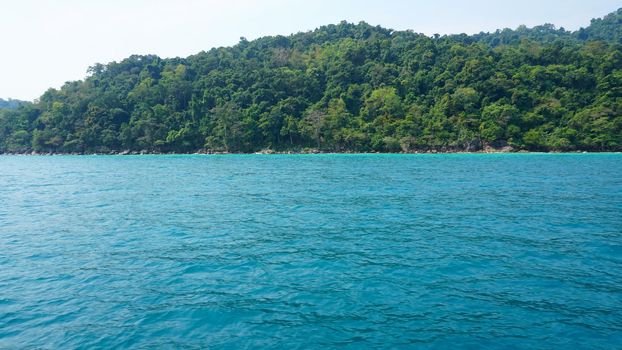 Travel by sea in Thailand by ship. View of the open ocean, green Islands and gray sky in smog. Green water with waves. Sailing between the Islands. Ship from different sides: stern, bow, rope, anchor.