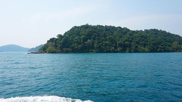 Travel by sea in Thailand by ship. View of the open ocean, green Islands and gray sky in smog. Green water with waves. Sailing between the Islands. Ship from different sides: stern, bow, rope, anchor.