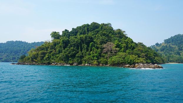 Travel by sea in Thailand by ship. View of the open ocean, green Islands and gray sky in smog. Green water with waves. Sailing between the Islands. Ship from different sides: stern, bow, rope, anchor.