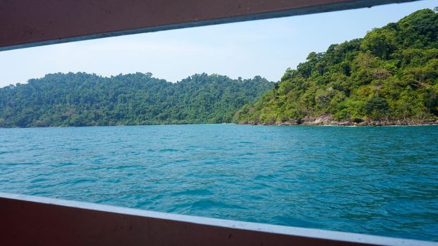 Travel by sea in Thailand by ship. View of the open ocean, green Islands and gray sky in smog. Green water with waves. Sailing between the Islands. Ship from different sides: stern, bow, rope, anchor.