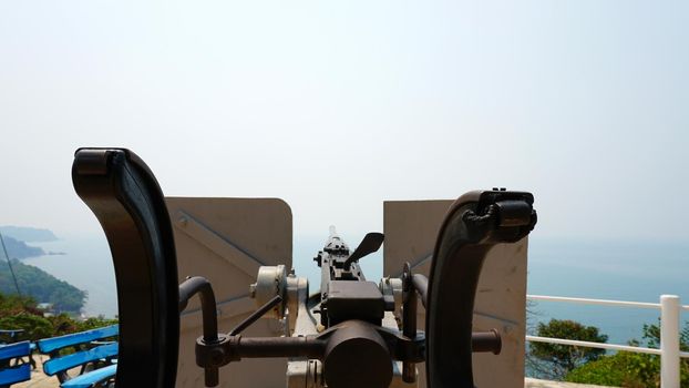 Observation deck with a military cannon. Machine gun on the shore. Protecting the island. Military weapons, army. History of the battle. A large caliber. Memory of the battle. Chang Island, Thailand.