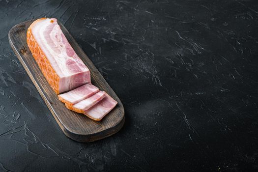 Smoked bacon, whole slab on black background with space for text.