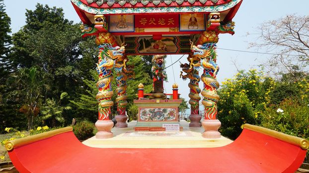 Chinese temple on Koh Chang island of Thailand. Bright colors of the temple, dragon and elephant sculptures. Flowers all around. The smoke from the sticks is coming. Hieroglyphs on the walls of bell.