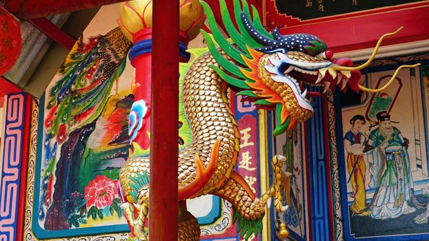 Chinese temple on Koh Chang island of Thailand. Bright colors of the temple, dragon and elephant sculptures. Flowers all around. The smoke from the sticks is coming. Hieroglyphs on the walls of bell.