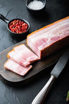 Bacon pancetta cut and sliced with herbs on black background.