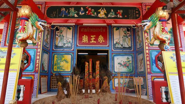 Chinese temple on Koh Chang island of Thailand. Bright colors of the temple, dragon and elephant sculptures. Flowers all around. The smoke from the sticks is coming. Hieroglyphs on the walls of bell.