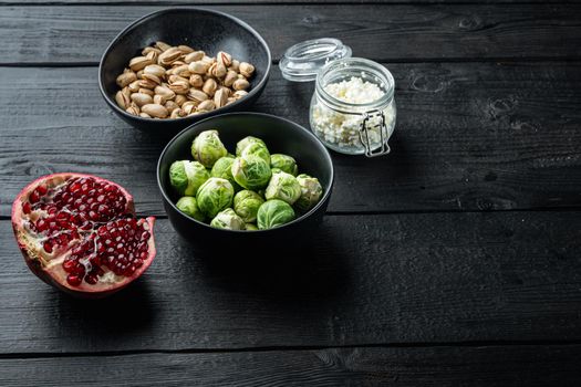 Brussels sprouts with pomegranate, cottage cheese and pistachios, on black wooden table with space for text