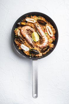 Traditional spanish seafood paella in pan on white background, top view, food photo.