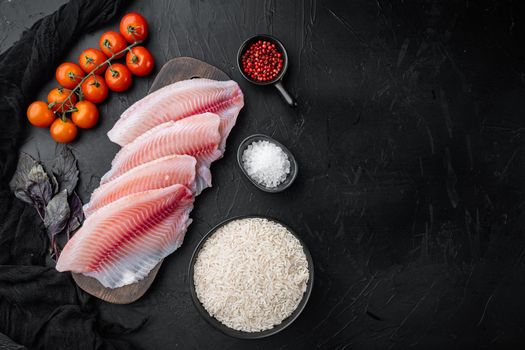 White fish fillet, with basmati rice and cherry tomatoes ingredients, on black background, top view with copy space for text