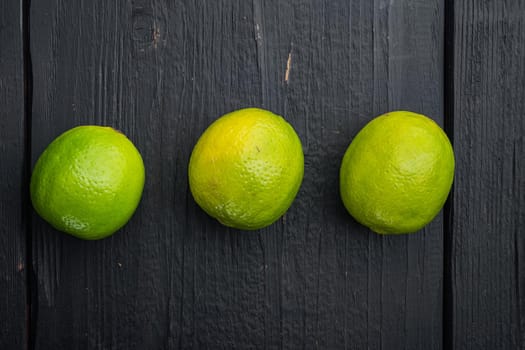 Ripe green lime set, on black wooden background, top view or flat lay