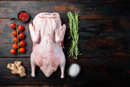 Raw whole farm duck meat on dark wooden background, flat lay, with space for text.