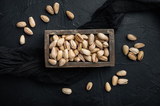 Shelled, unsalted pistachios, on black textured background, flat lay