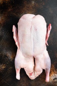Raw whole farm duck meat on old dark background, top view.