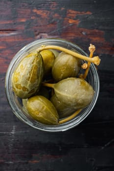 Capers, marinated in oil, on old wooden table, flat lay