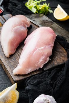 Raw crumbet chicken fillet with ingredient with butcher knife on black wooden table