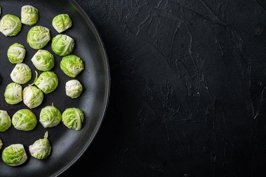 Raw brussels sprouts, on black textured background, top view with space for text