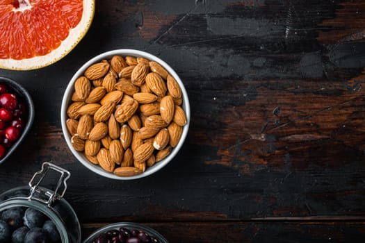 Almonds nuts in bowl, top view on dark wooden background, with copy space.