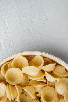 Dried pasta shells in bowl, on white background, top view with copy space for text