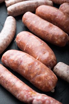 Fresh raw pork, beef and chicken sausages, on black background.
