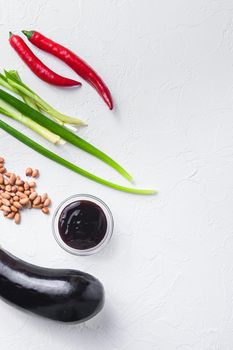 Baked aubergine ingredients, for cooking or grill chili pepper, eggplant, sauce, nuts on white background top view space for text