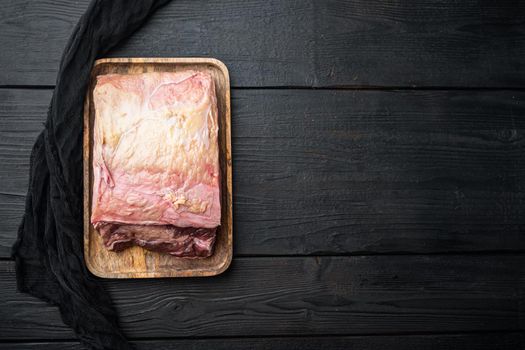 Strip steak, marbled beef raw meat, on black wooden table, on black wooden table, top view, with copy space for text