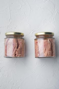 Tuna fillet meat in glass jar, on white background, flat lay with copy space for text