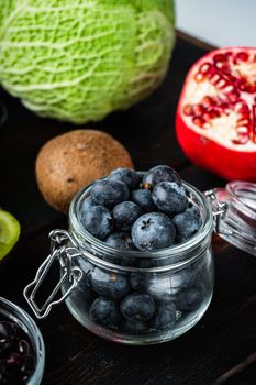 Ripe blueberry in glass jar on dark wooden background.