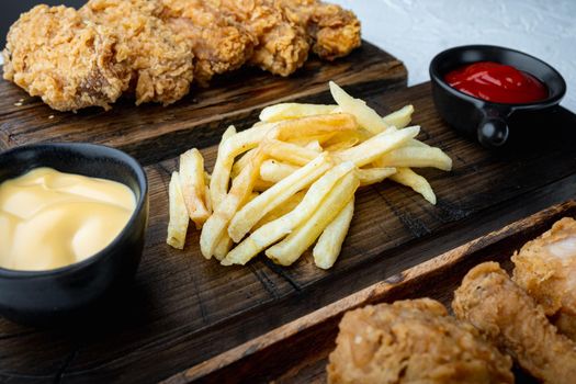 Crispy french fries with breaded chicken on white background.