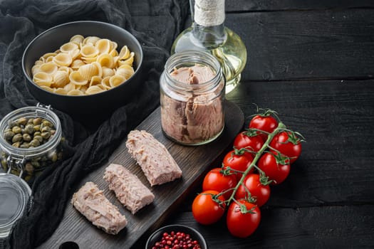 Delicious lumaconi pasta meal with tuna and baby capers, on black wooden table with copy space for text