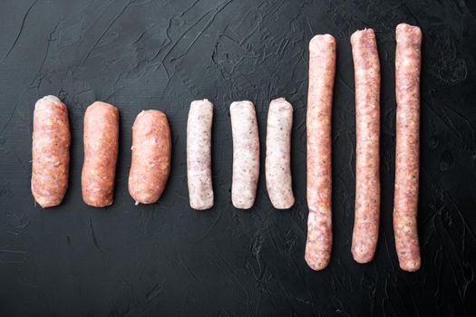 Raw homemade sausages, flat lay, on black background.