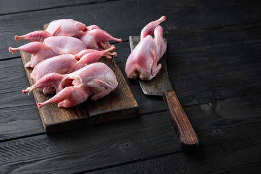 Fresh organic whole quail meat, on black wooden background with space for text