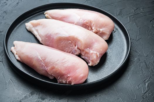 Chicken raw fillets, on black background with space for text