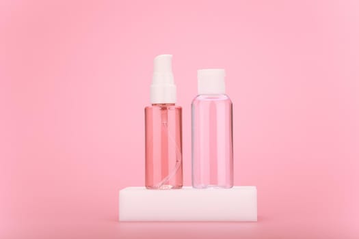 Minimalistic still life with two beauty products for skin care in transparent bottles on bright pink background
