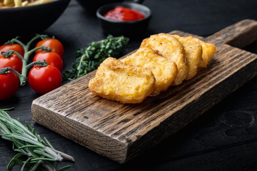 Nuggets breaded on black wooden background.