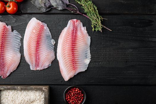 White fish fillet, with basmati rice and cherry tomatoes ingredients, on black wooden background, top view with copy space for text