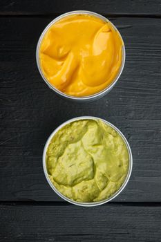 Canned cheese and guacamole sauce in can, on black wooden background, top view or flat lay