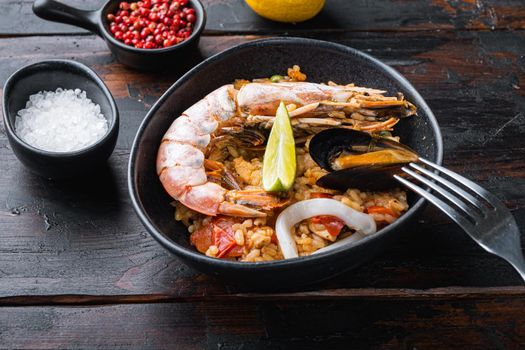 Traditional spanish paella with seafood, prepared in wook on old dark wooden background, food photo.