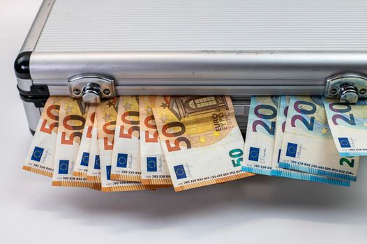 50 and 20 euro banknotes on aluminum briefcase on white background