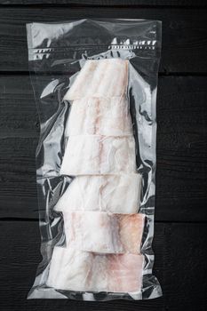 Haddock fish skinless in vacuum package, on black wooden table